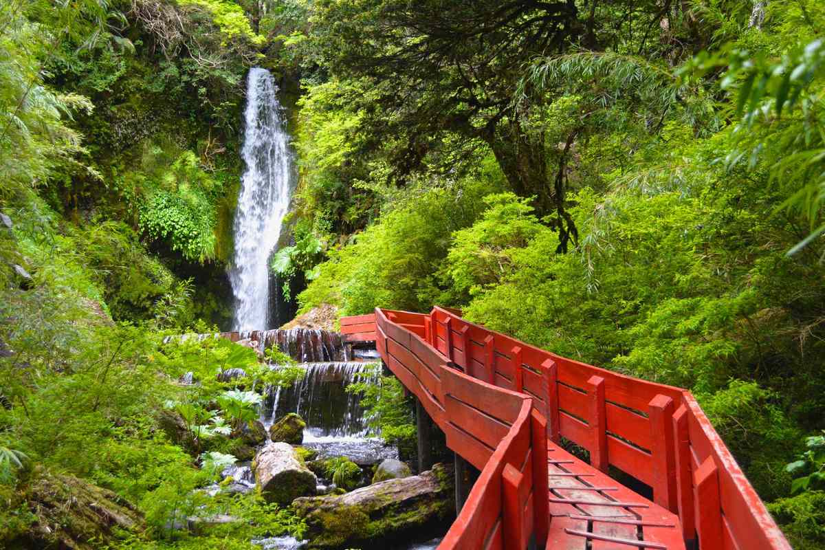 A red boardwalk leading to a waterfall
