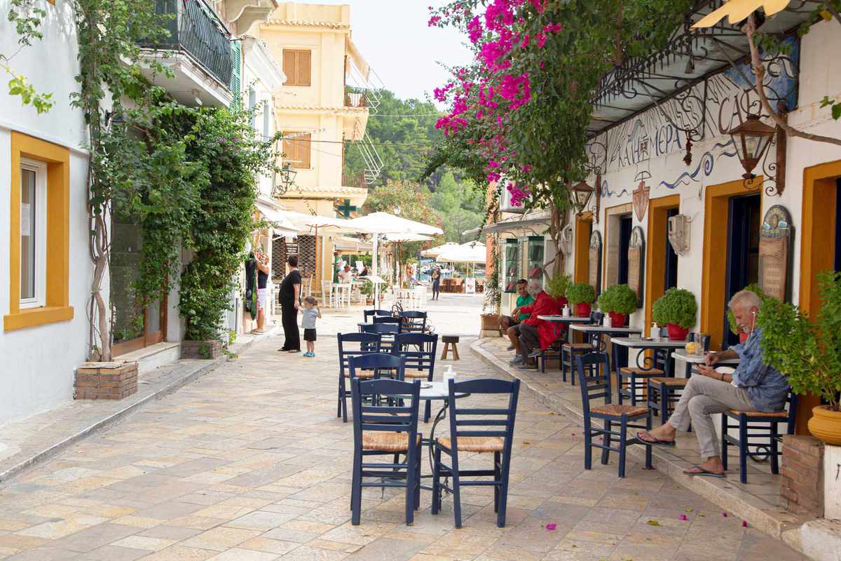 A small Greek street lined with cafe tables