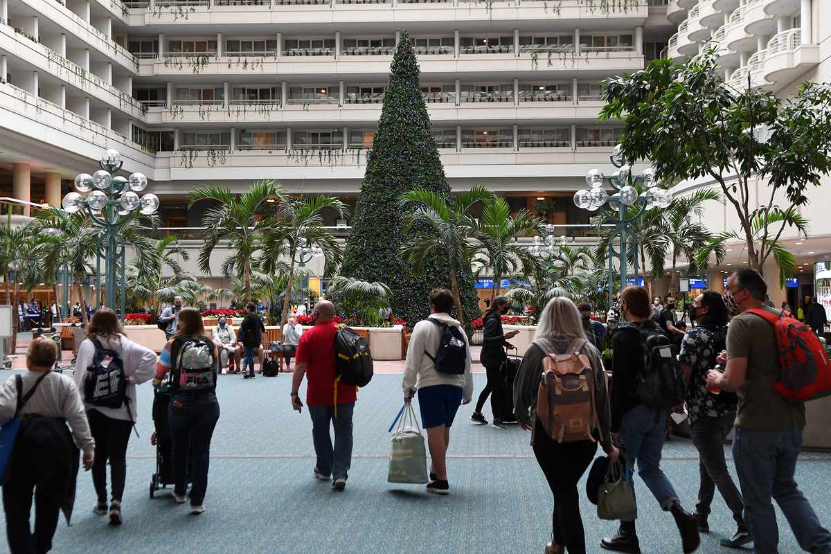 Travelers wearing face masks arrive at Orlando International Airport on the day before Christmas