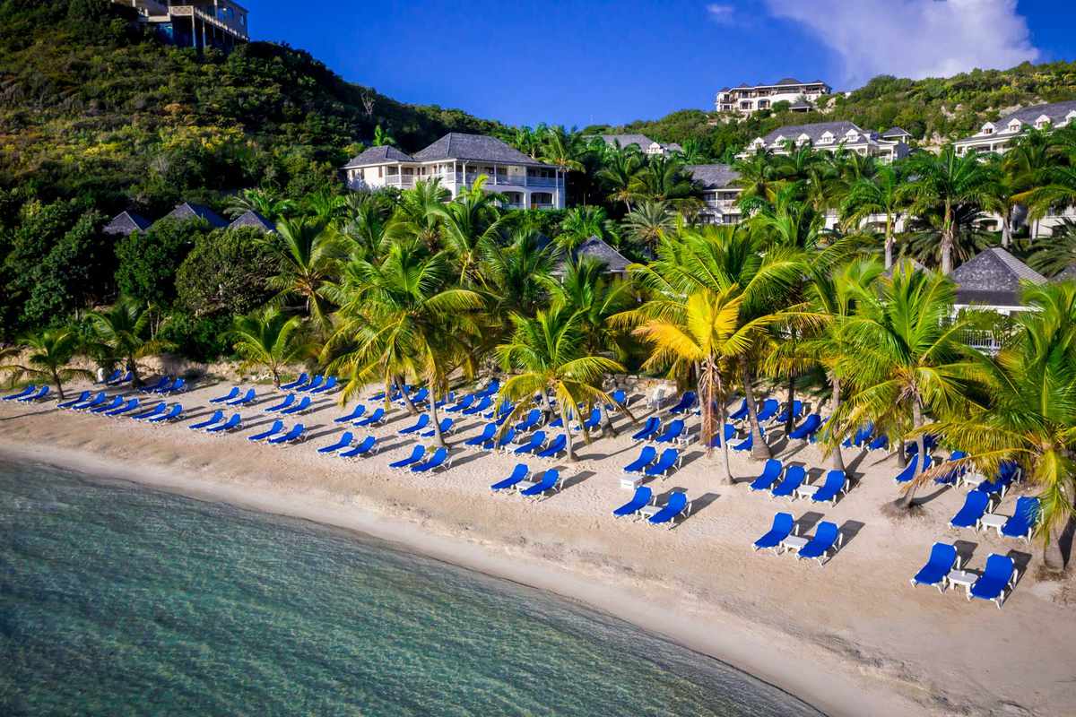 Aerial view of the beach at Nonsuch Bay Resort in Antigua, filled with blue beach loungers