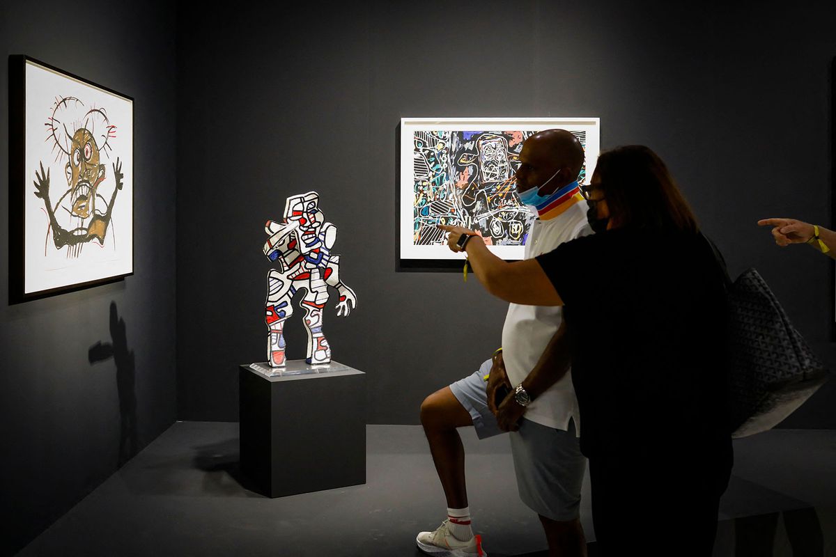 People look at artworks during the first day of the Art Basel 2021 exhibition at the Miami Beach Convention Center in Miami Beach, Florida,
