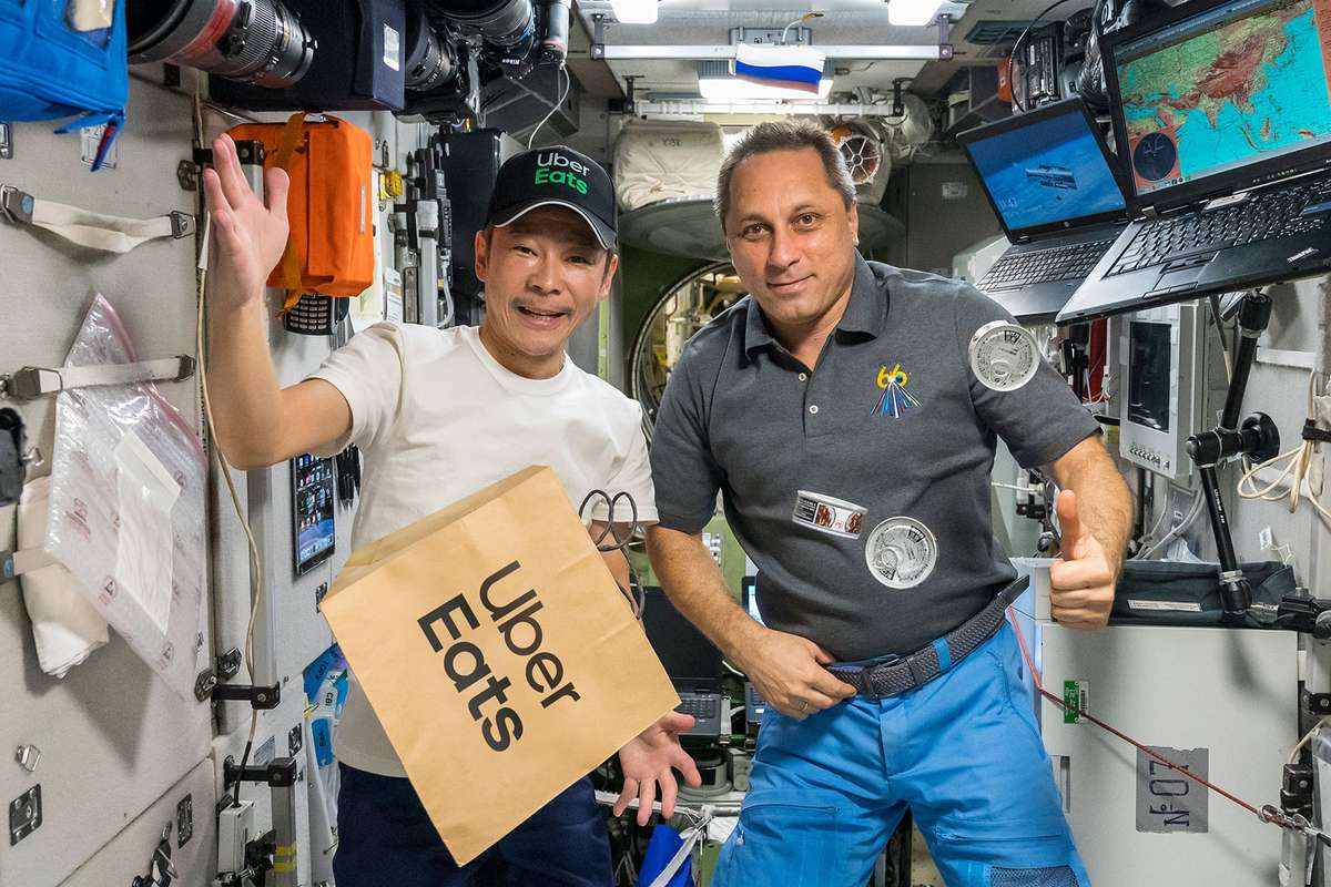 Yusaku Maezawa & ISS Astronaut in space with an Uber Eats bag