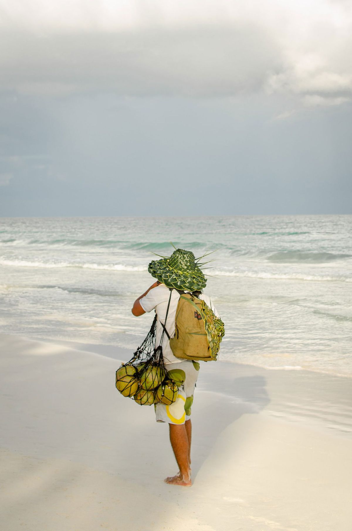 Person with a bag of coconuts on the beach in Tulum