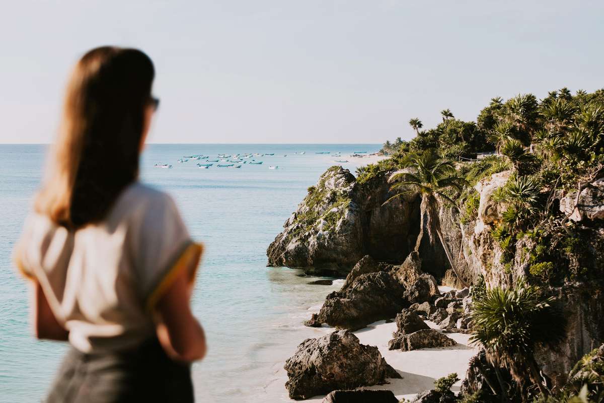 Blurry figure of person in the foreground staring at the cliffs and ocean of Tulum