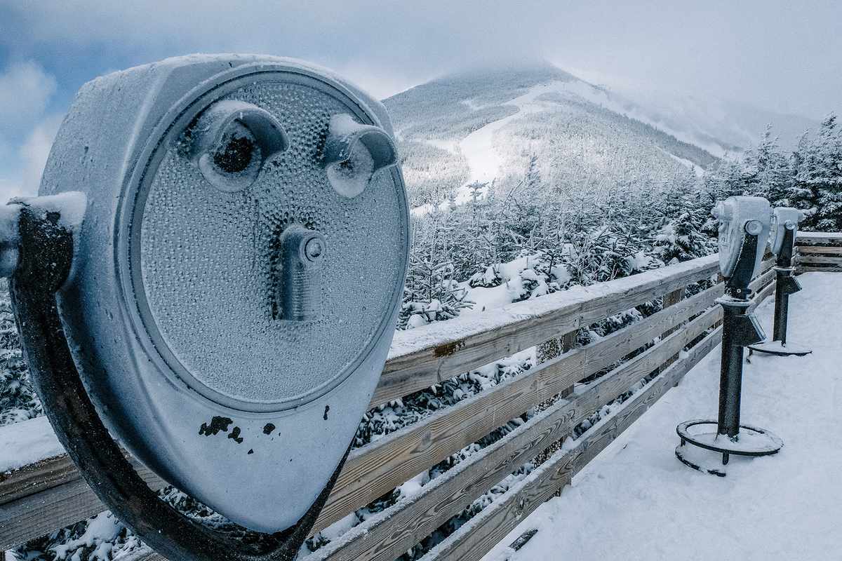 Snow covered coin-operated binoculars against mountains at observation point at Lake Placid