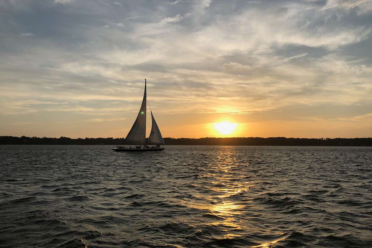 A Vagabond Cruise sailboat on the water during sunset