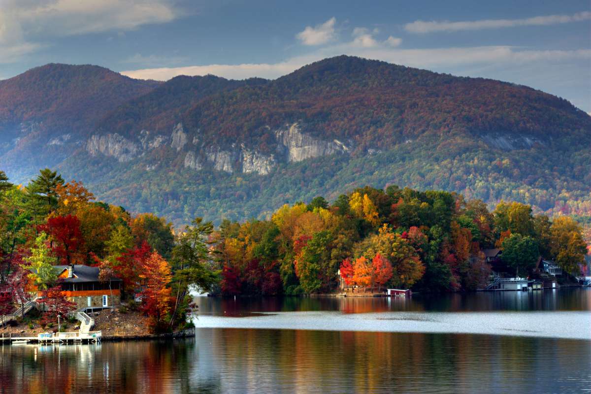 Brilliant Fall colors reflect in the still waters of Lake Lure with the Blue Ridge Mountains forming a backdrop, North Carolina.