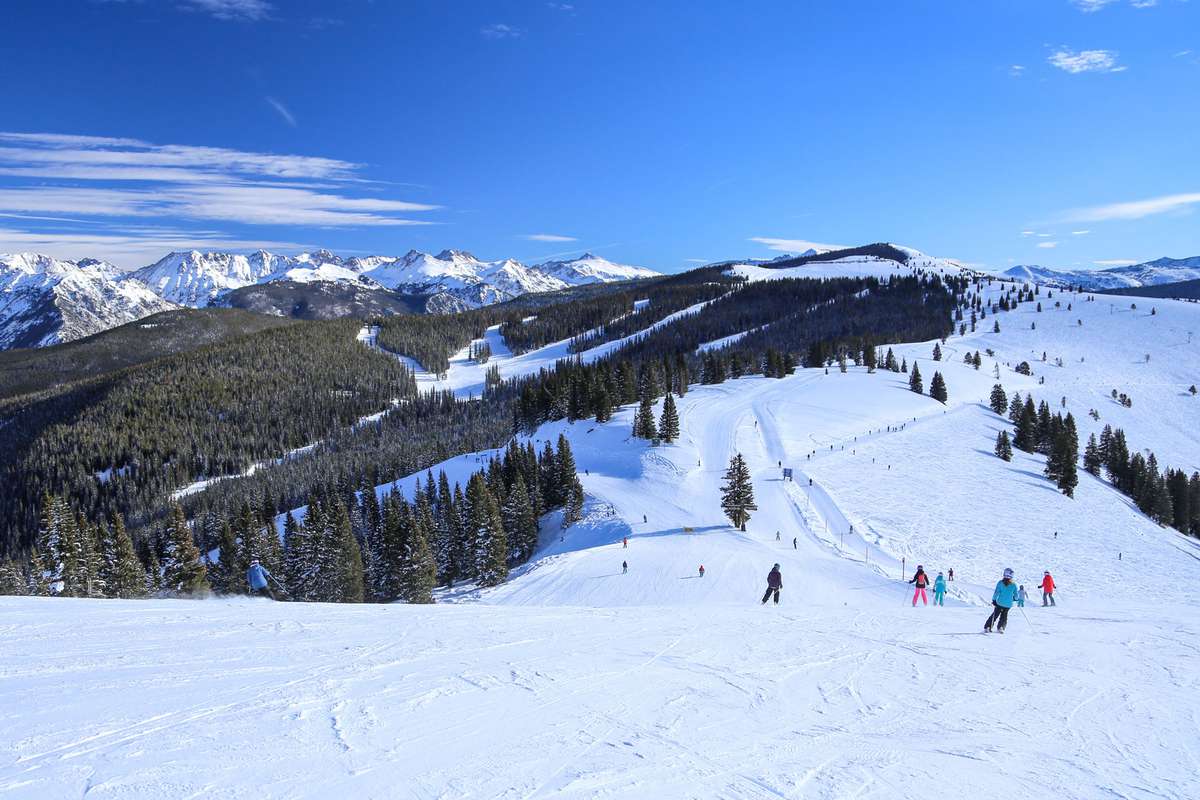 Alpine downhill skiers in the snow covered Rocky Mountains of Vail