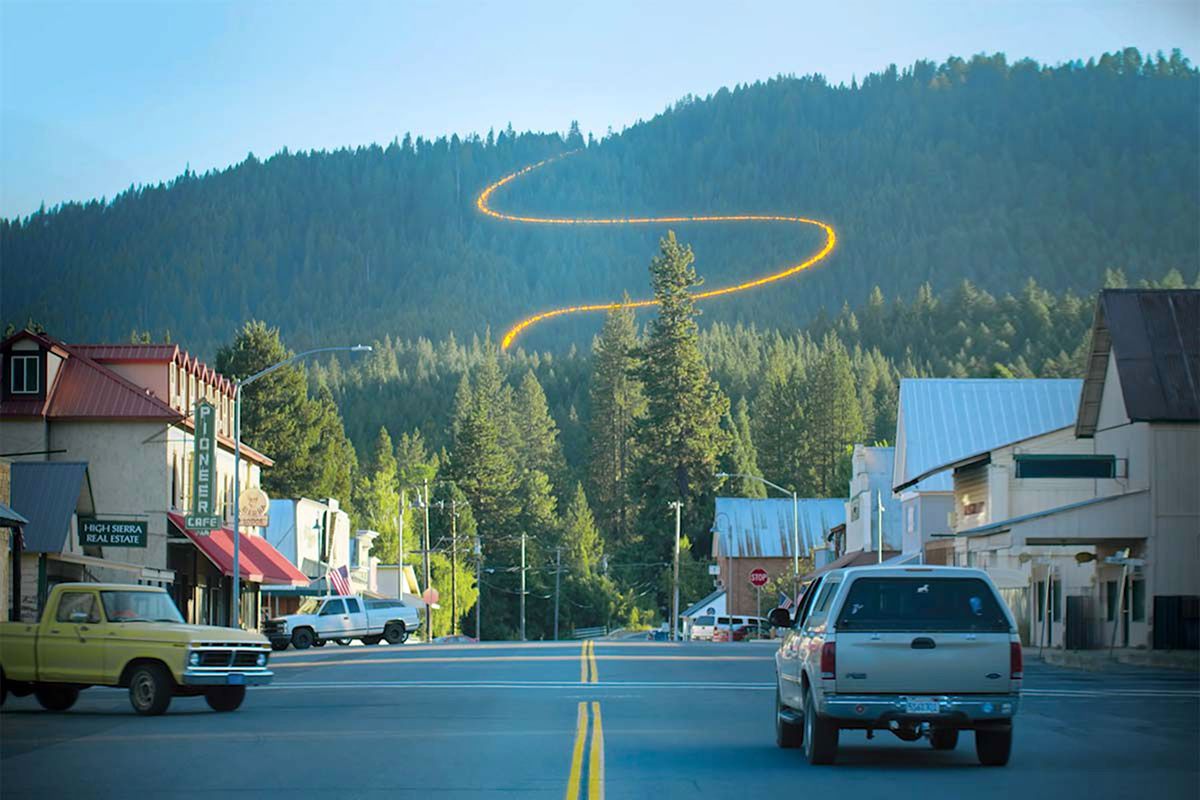 View of Main Street in mountain town with glowing line on the mountain, indicating trail lines