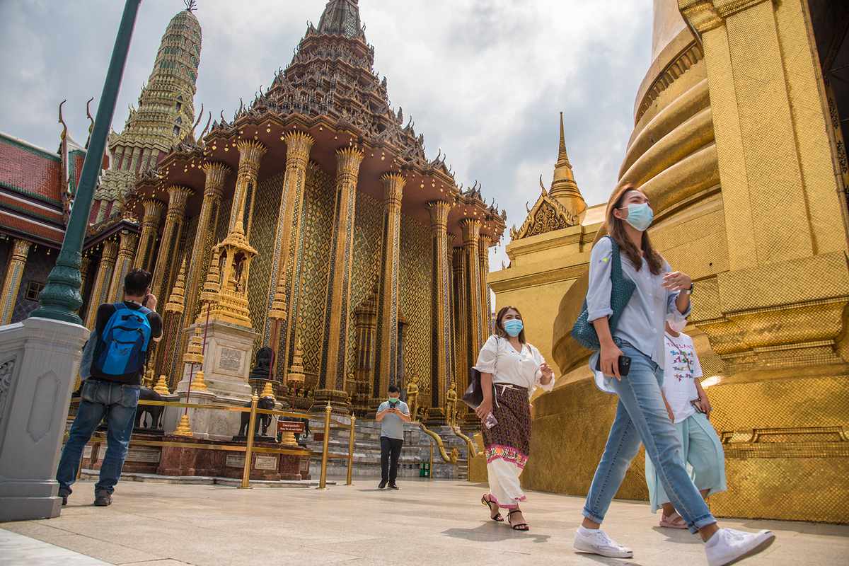 Tourists wearing face masks visit the Grand Palace.