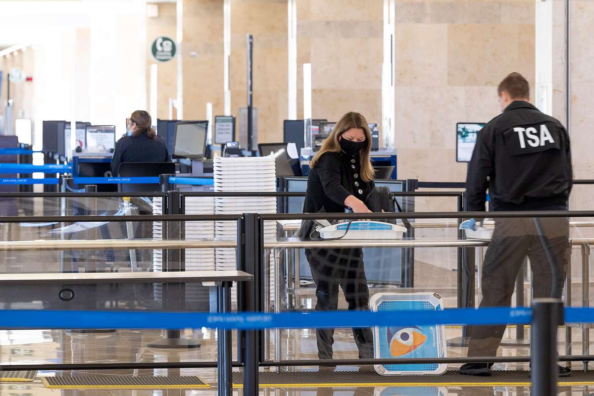 A TSA agent helps a traveler through security at a nearly deserted checkpoint at John Wayne Airport in Santa Ana, CA