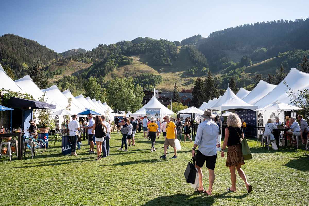 People walk the grounds between white tents at the Food & Wine Classic in Aspen