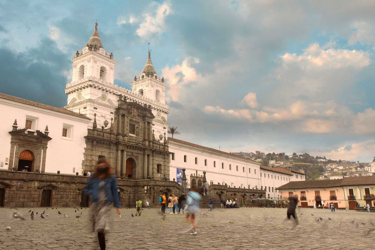 Tourists walking at sunset in front of the San Francisco church located in the historic center of Quito