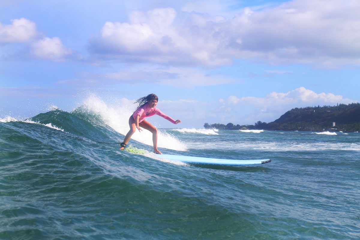 A little girl surfing with North Shore Surf Girls