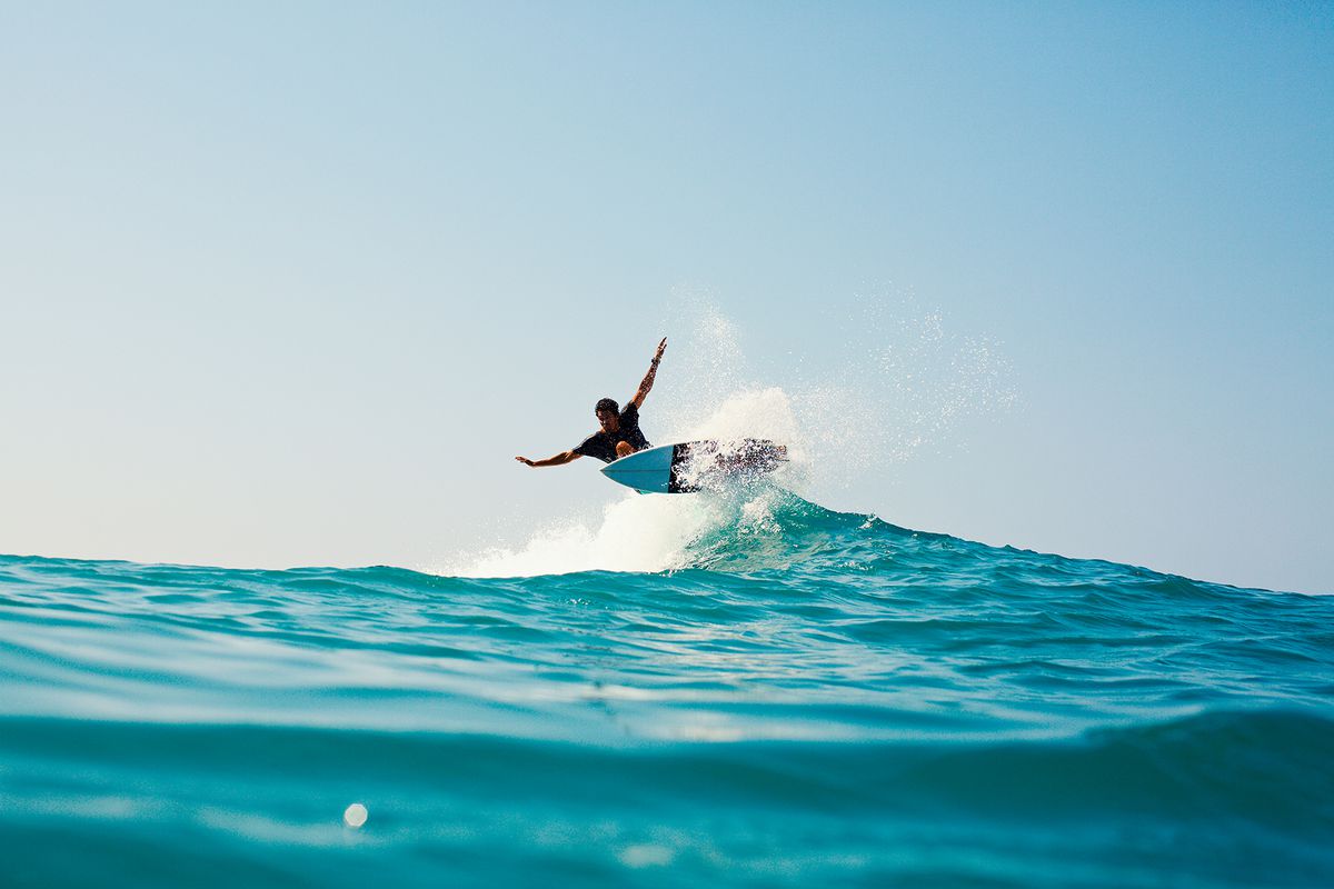 A surfer riding turquoise blue ocean wave in La Ticla