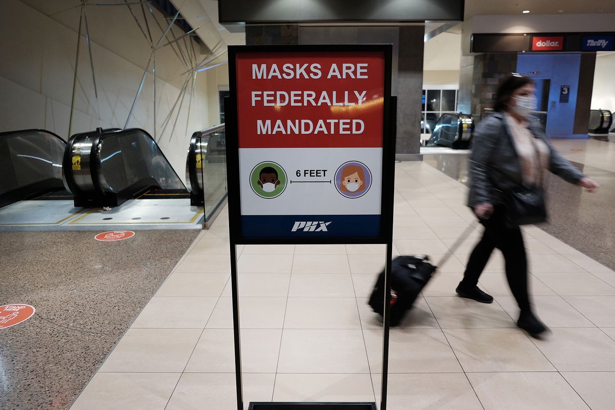 A sign reminding travelers masks are mandated in an airport