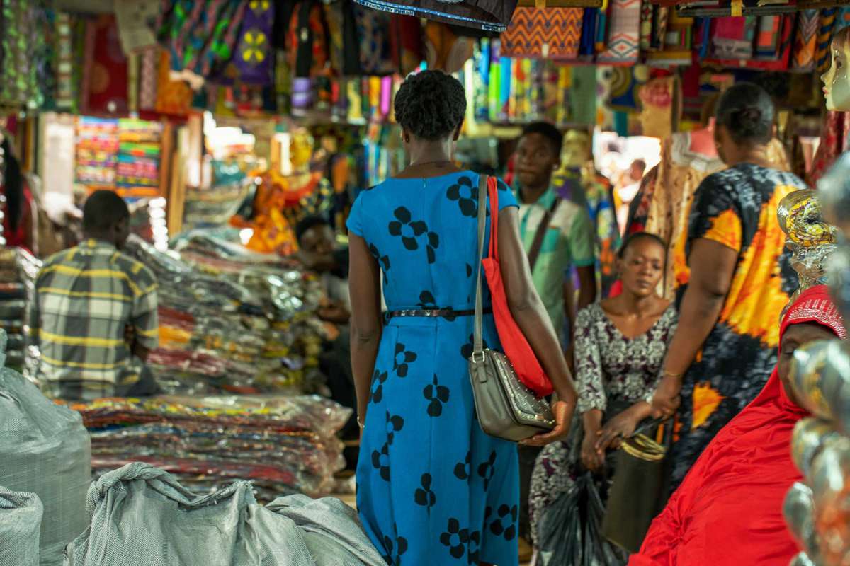 A woman walks through a market wearing a dress by brand 4