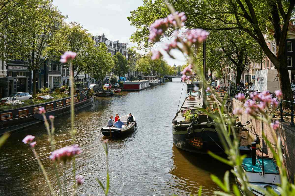 A boat on Amsterdam's Prinsengracht Canal, viewed through greenery on the riverbank