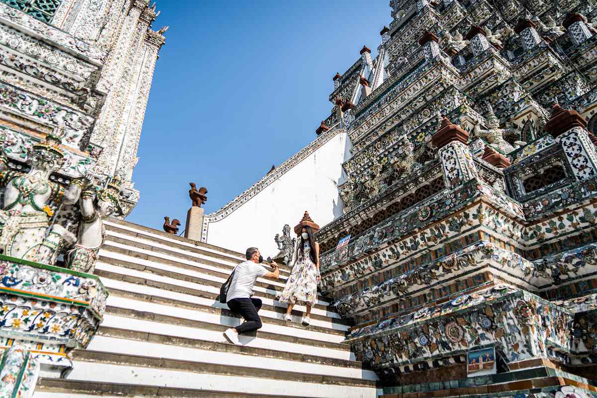 Tourists take photos on the stair steps of Wat Arun in Bangkok.