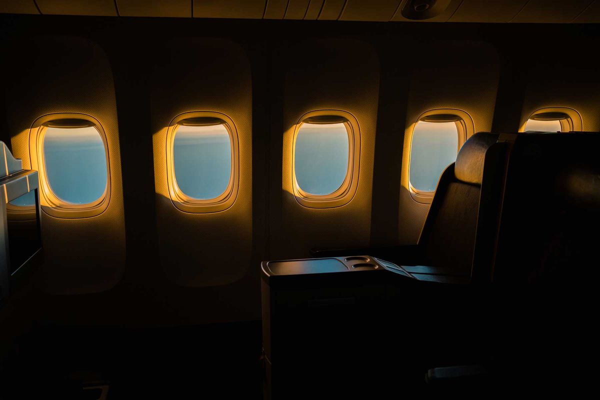 Row of airplane windows during golden hour in a first class section of airplane cabin