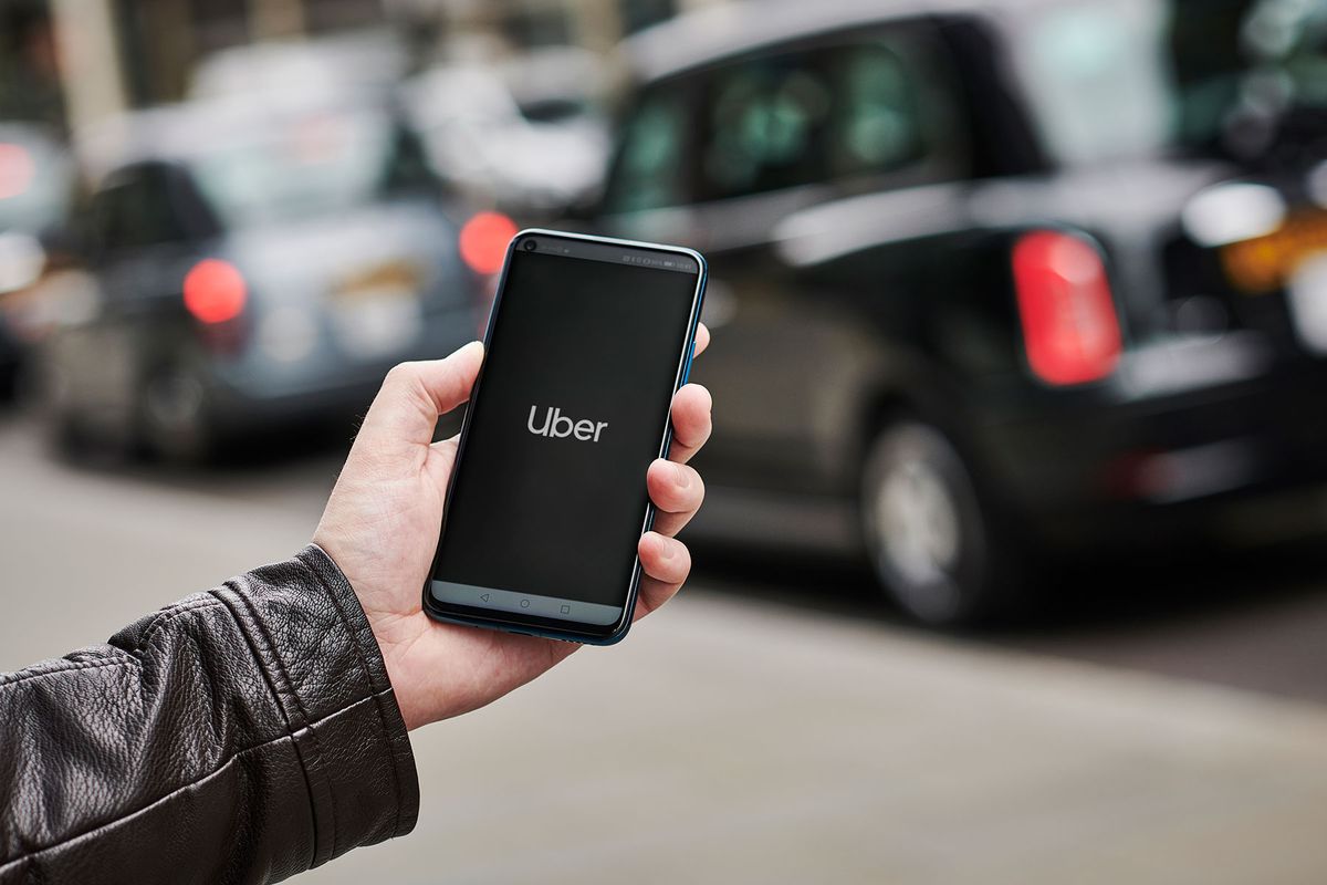 a man holding up a smartphone with the Uber transport app visible on screen in London