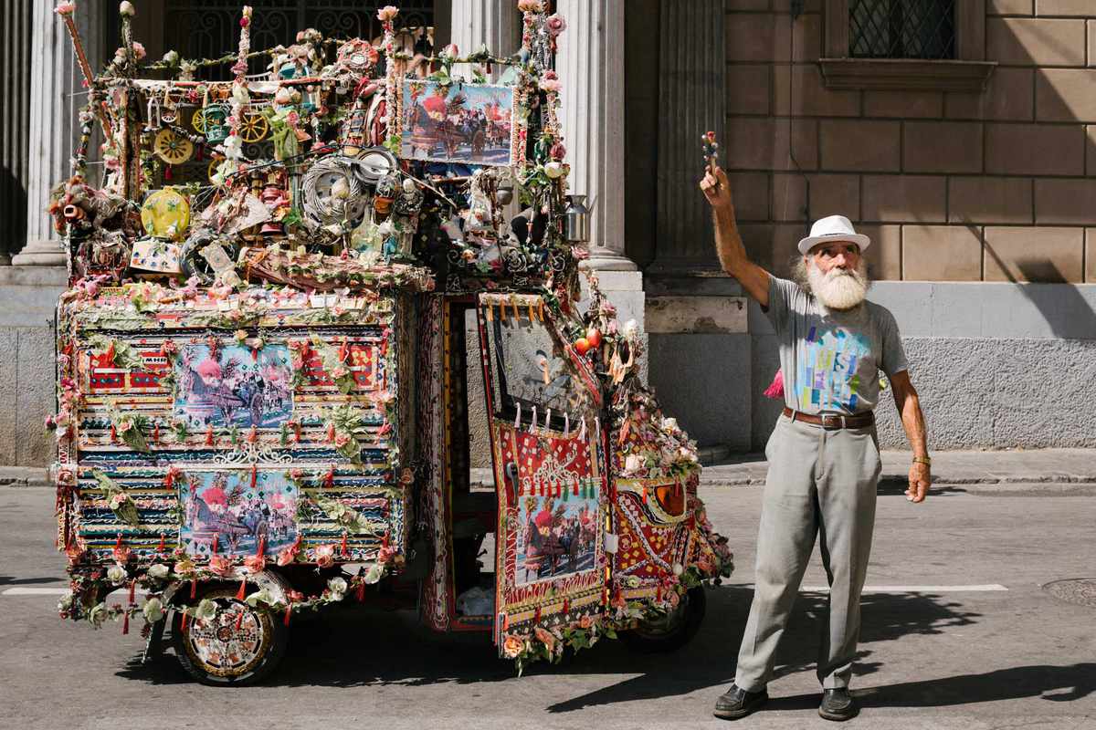 A man in front of a car decorated in honor of Santa Rosalia, on the streets of Palermo