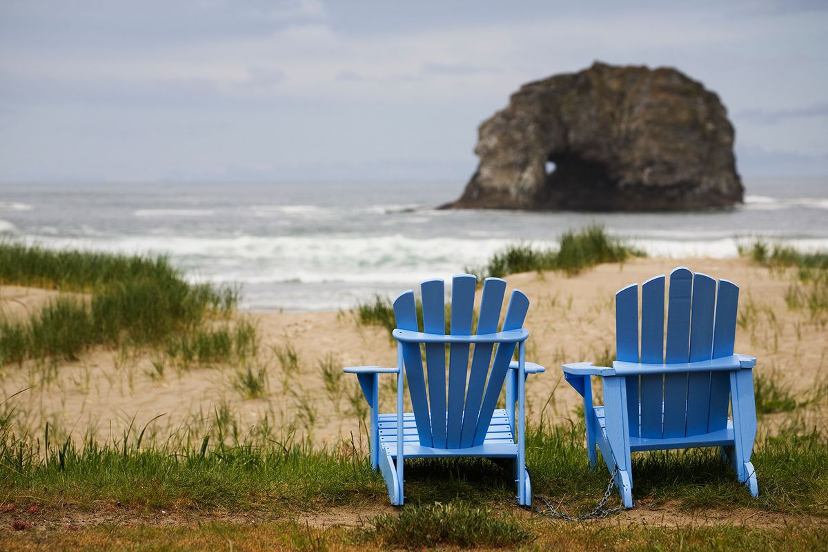 Two Blue Adirondack Chairs On A Grassy Rockaway Beach in Oregon