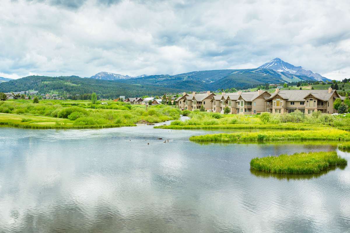 Panoramic view of Big Sky, Montana with pond, golf course, Lone Mountain and condos.