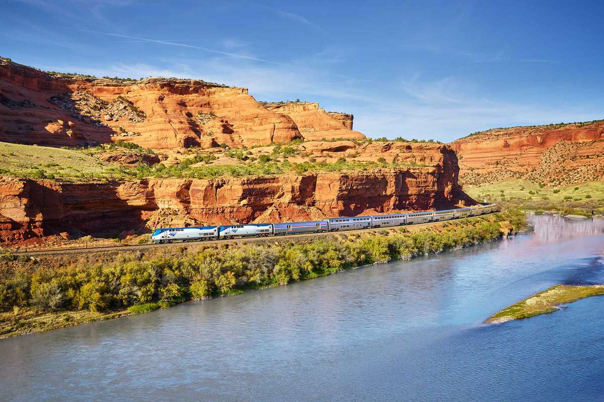 An Amtrak train, Zephyr, goes through desert valley alongside a river in California
