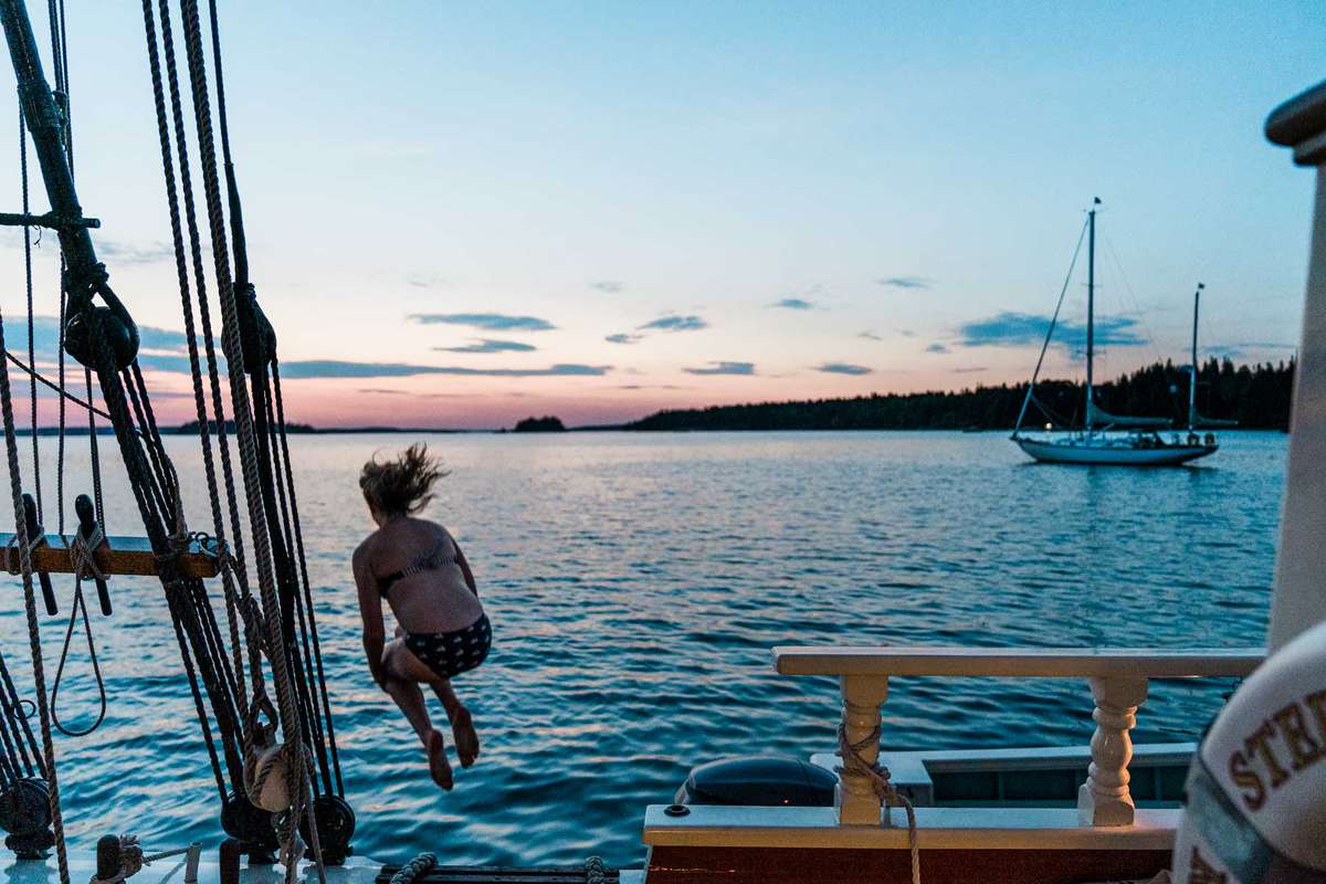 A woman jumps off of a wooden boat deck