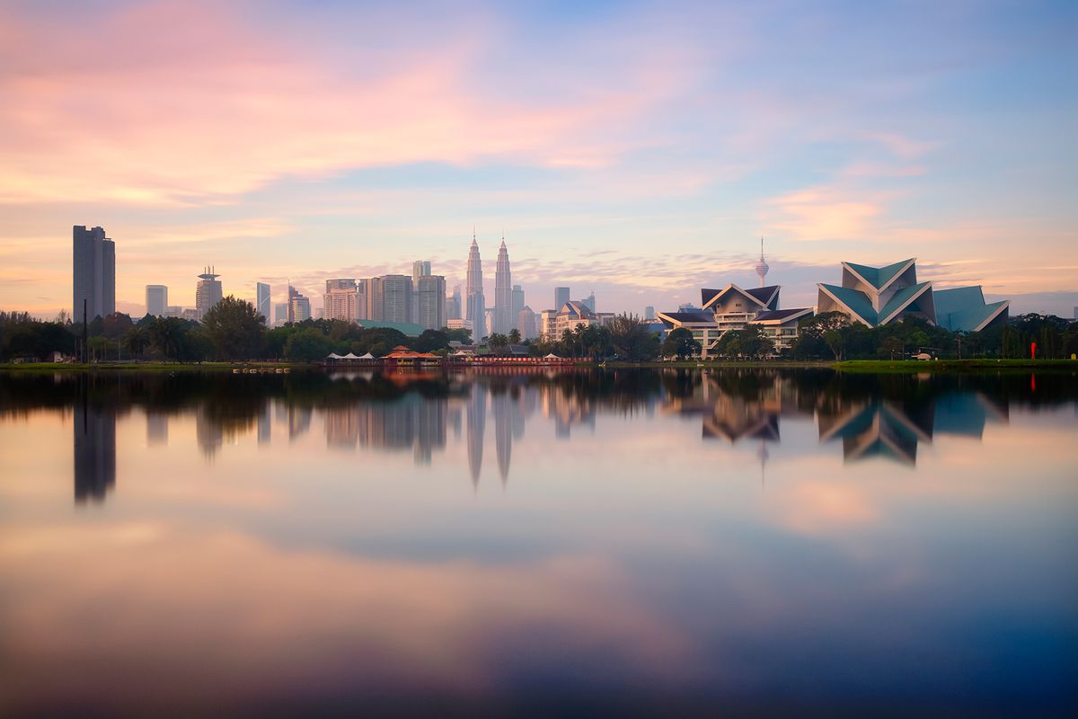 Panoramic Kuala Lumpur cityscape reflects on lake from Titiwangsa park in Malaysia