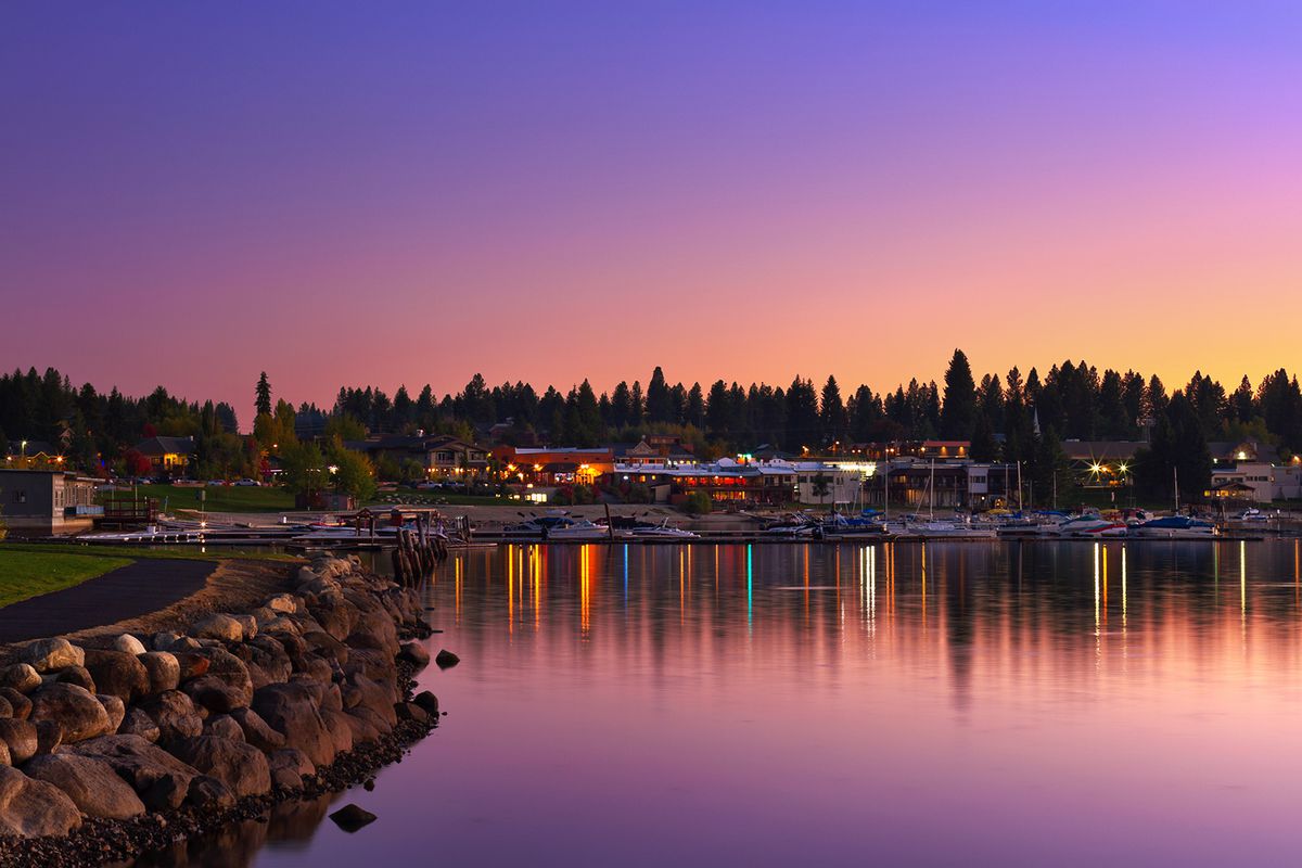 Sparkling lights of small vacation town McCall, Idaho, reflected in calm waters of Payette Lake at sunset on autumn evening