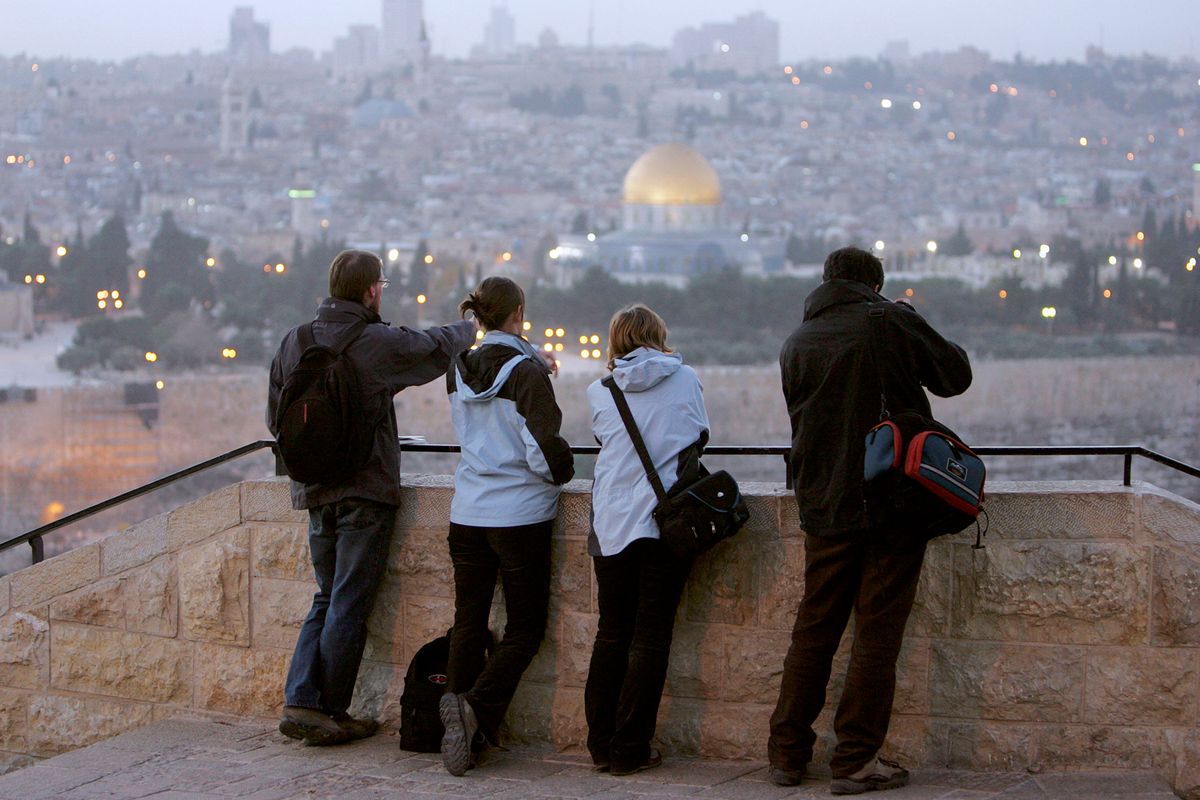 Tourists stand at the Mt. of Olives as evening falls over the Old City in Jerusalem, Israel.