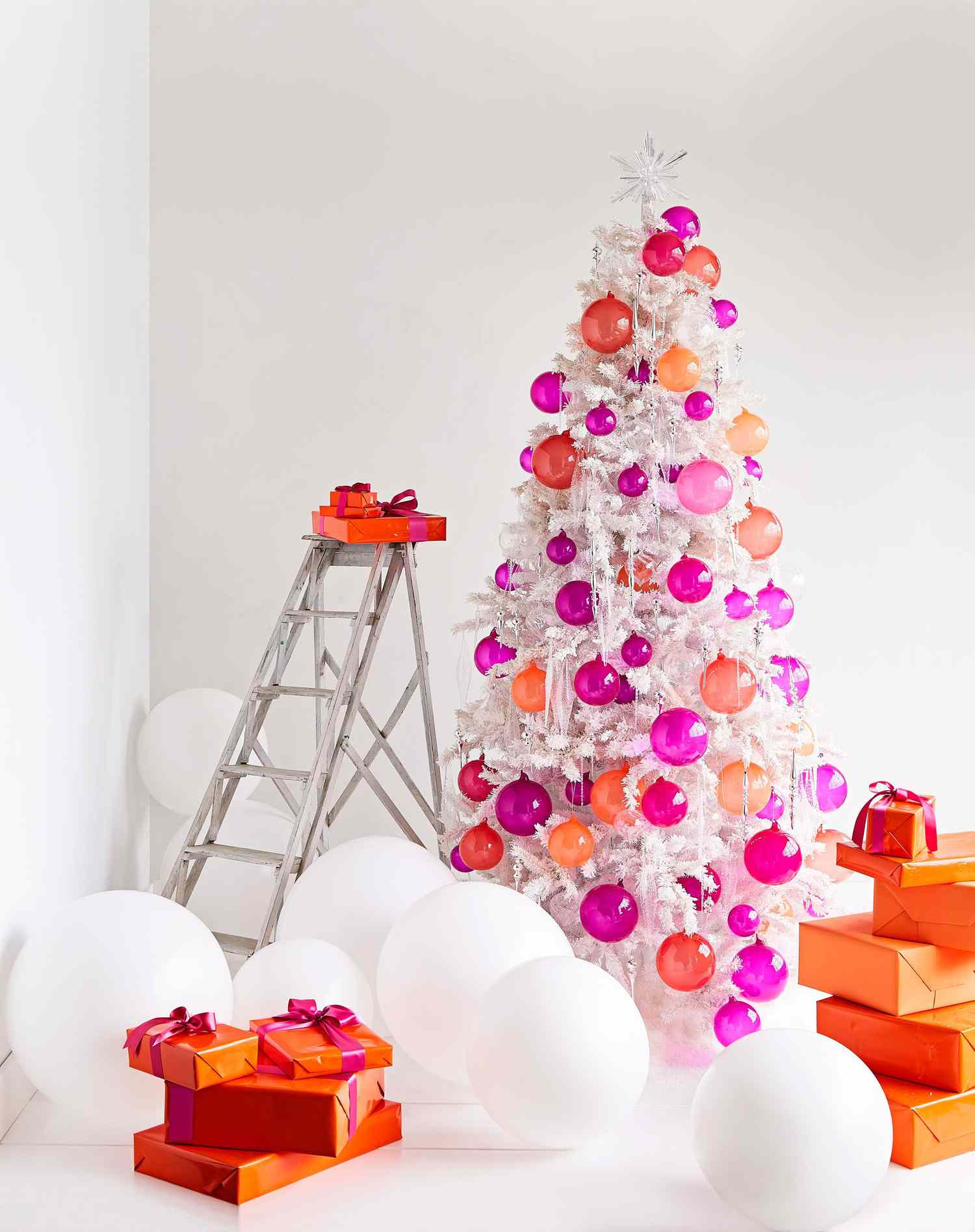 white christmas tree decorated with orange and pink handblown glass balls