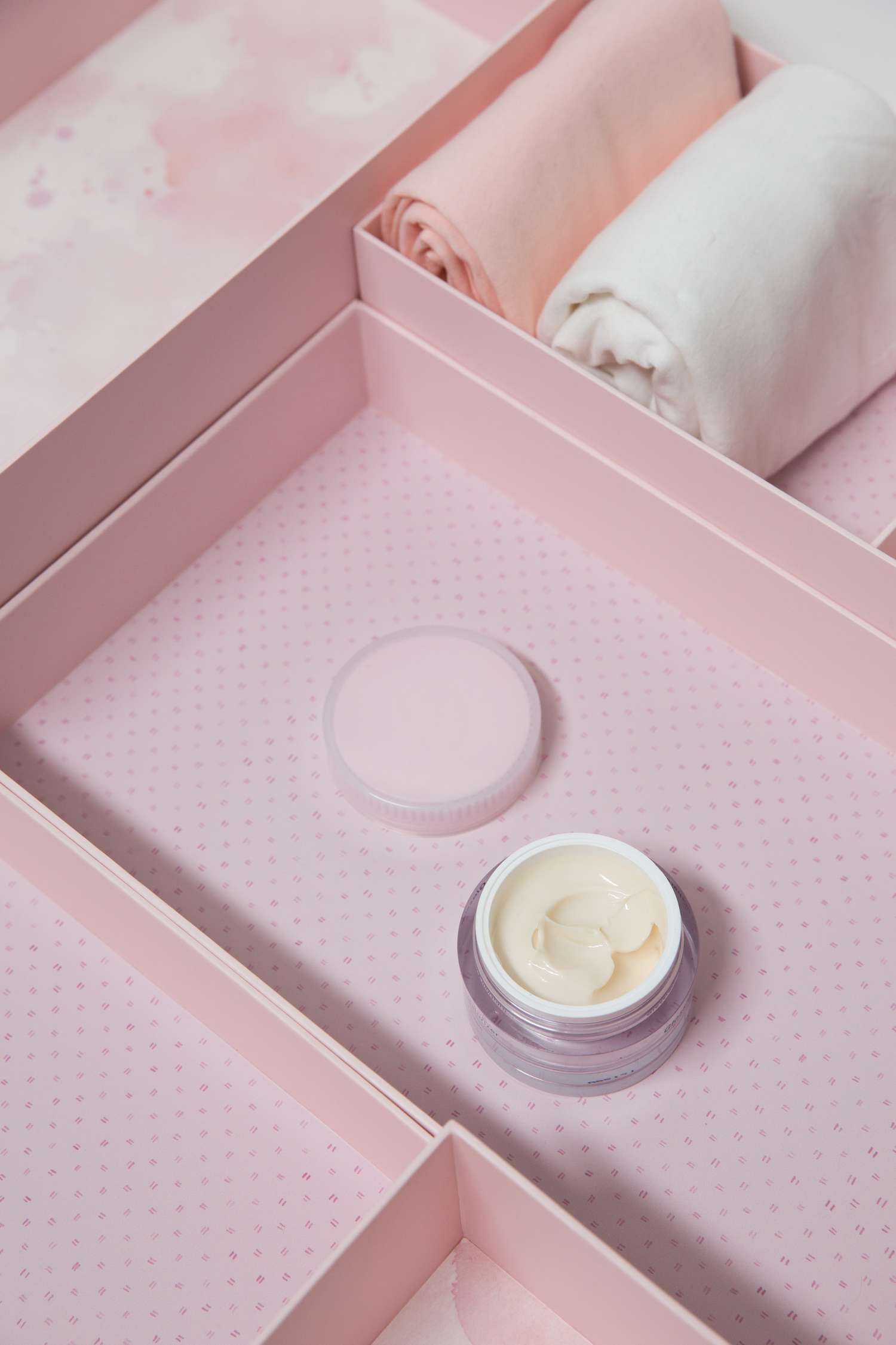 pink marie kondo box holding makeup and rolled clothes