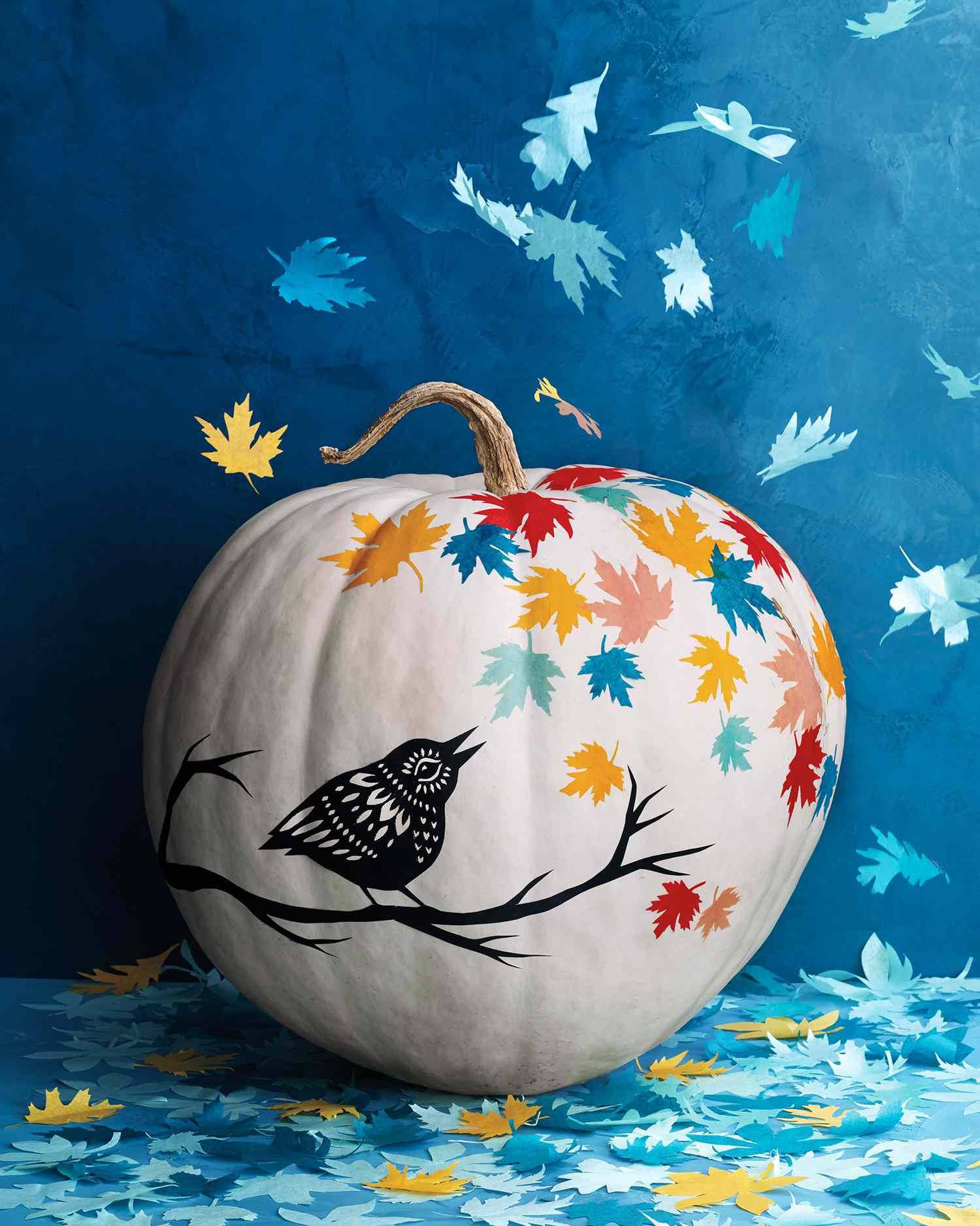 white pumpkin with bird and branch against teal background