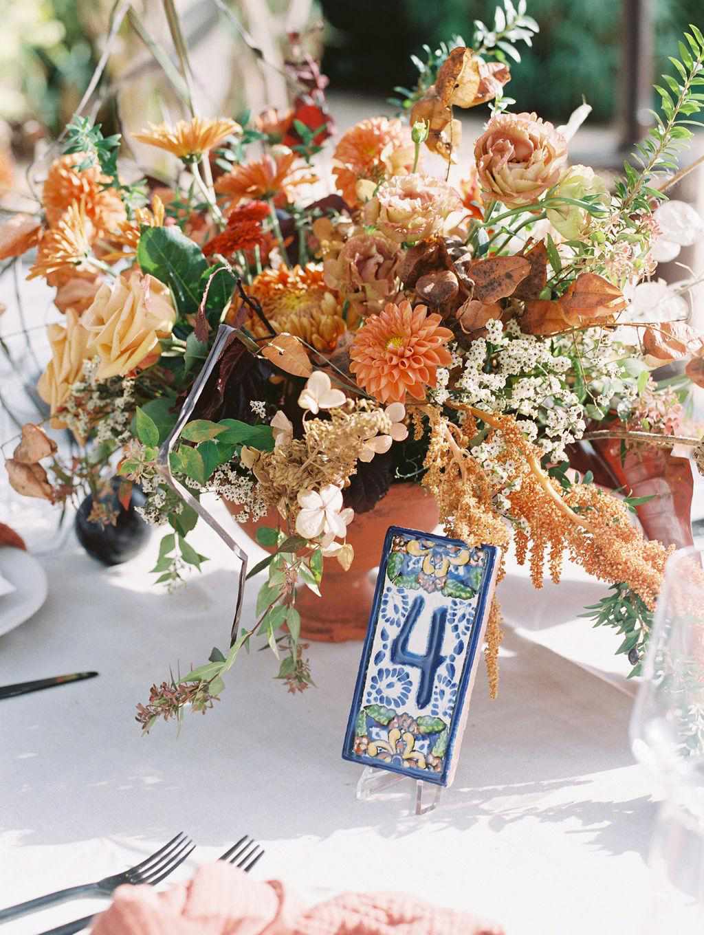 dahlias rust astilbe roses fall floral arrangement blue tile table number