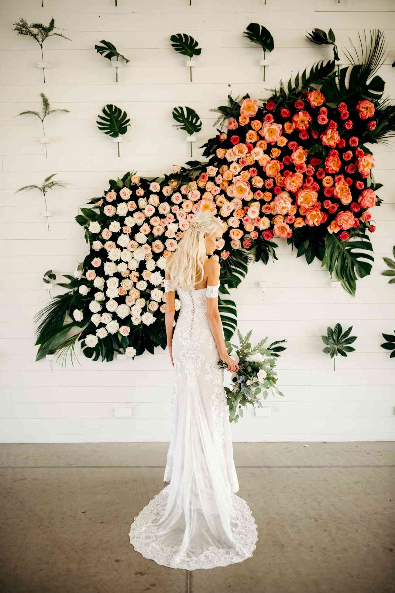 bride standing in front of orange ombre floral wall display