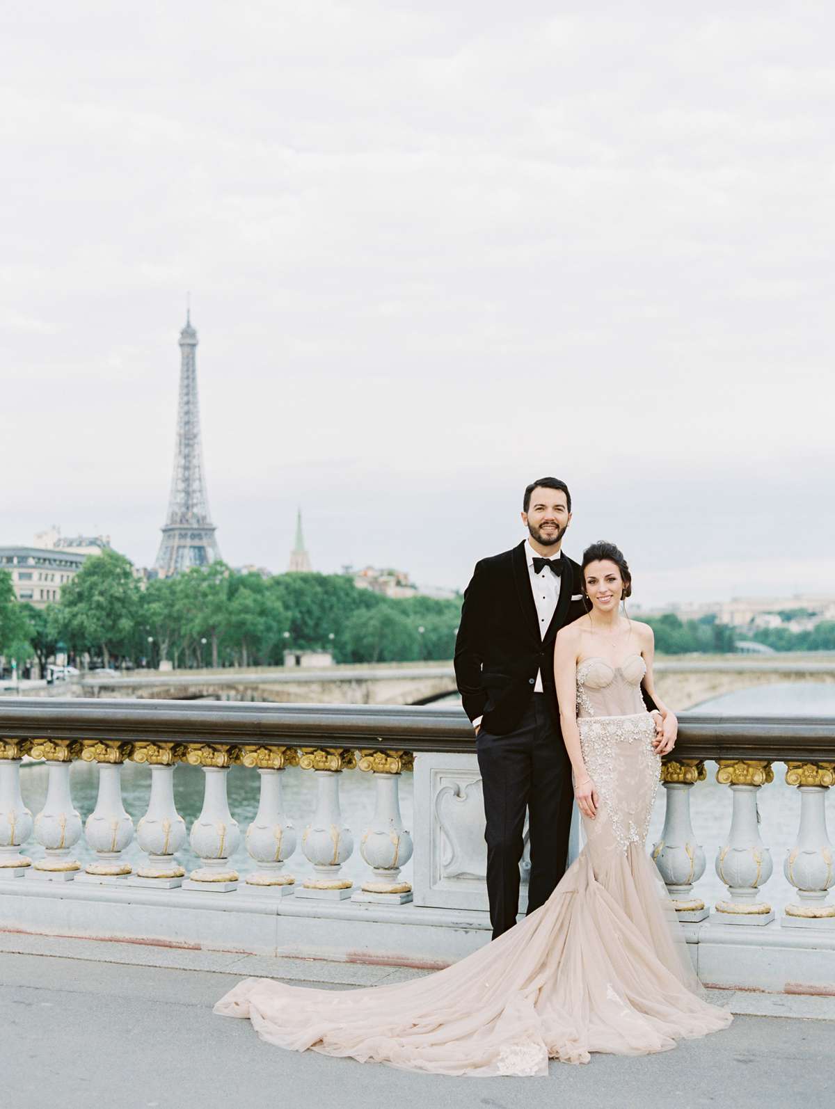 bride and groom posing on bride in front of eiffel tower