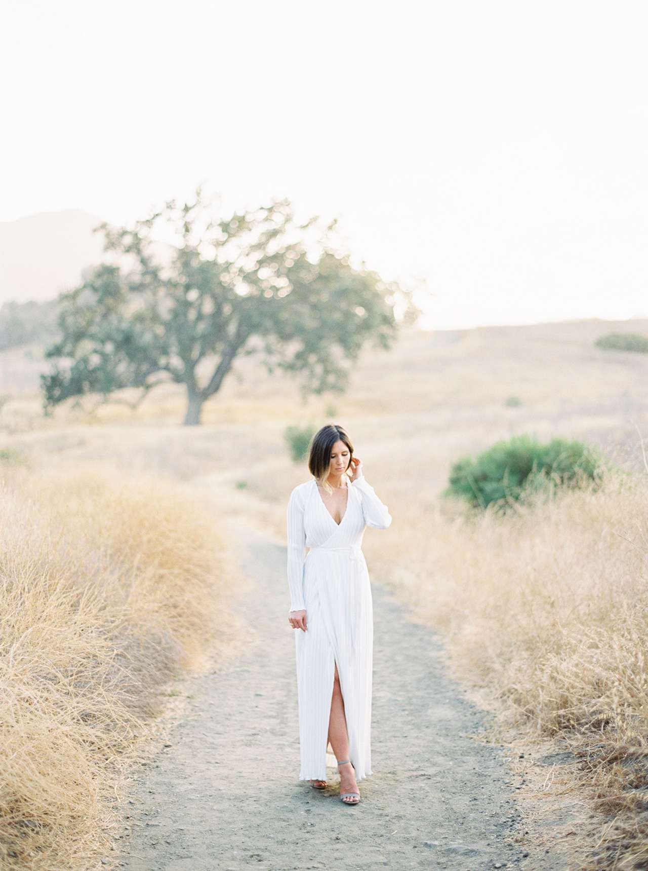 woman walking down sand bath long white v-neck dress