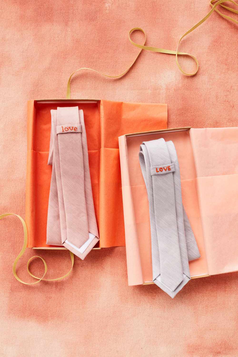 两条领带装在橙色盒子里，上面绣着爱情