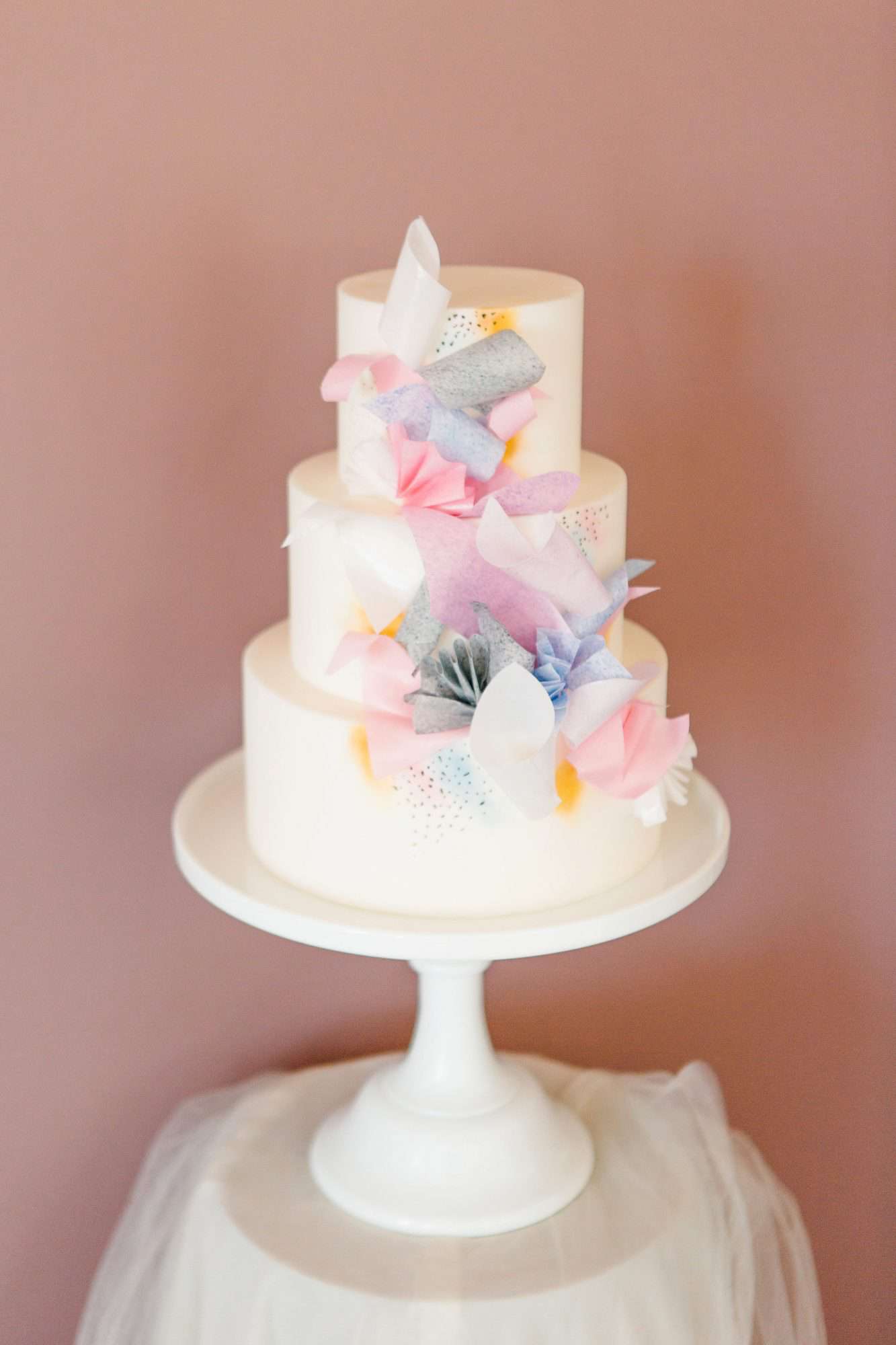 3-tier white cake decorated with pastel paper pieces