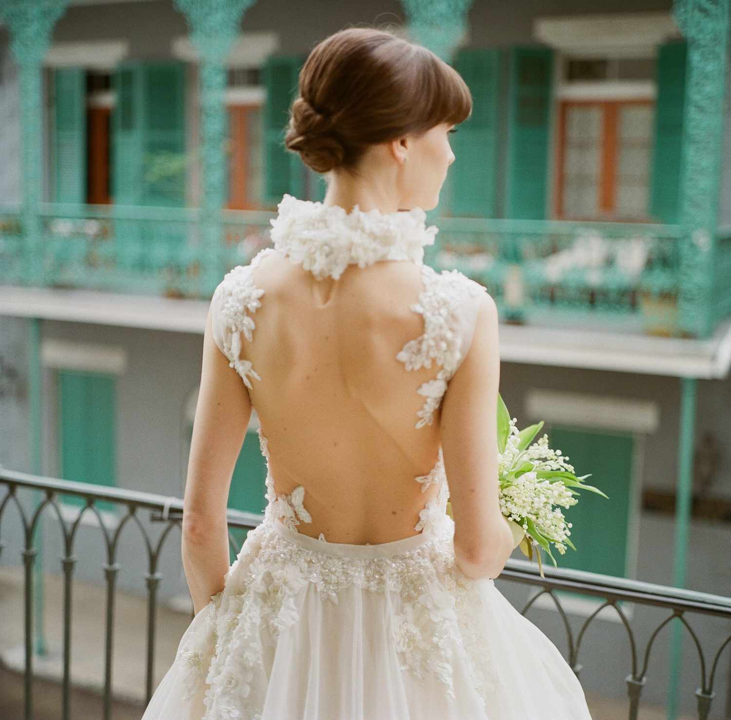 A Bride Wearing a Wedding Dress with a Dramatic Back Looking Over a Balcony