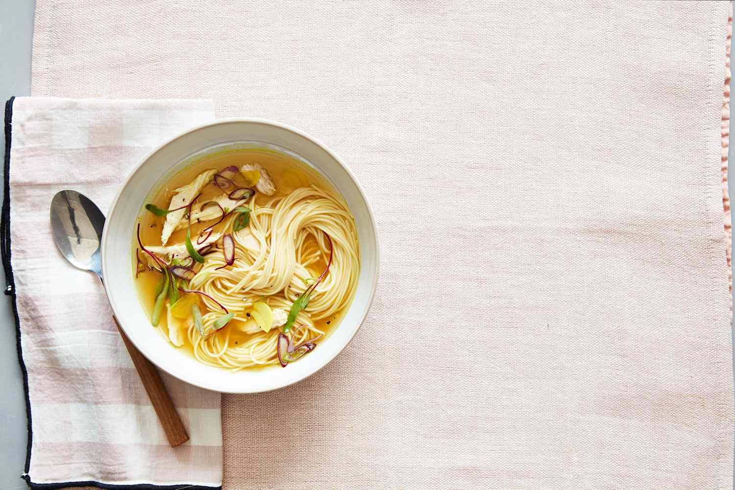tumeric ginger chicken soup with noodles in a bowl on a pink cloth
