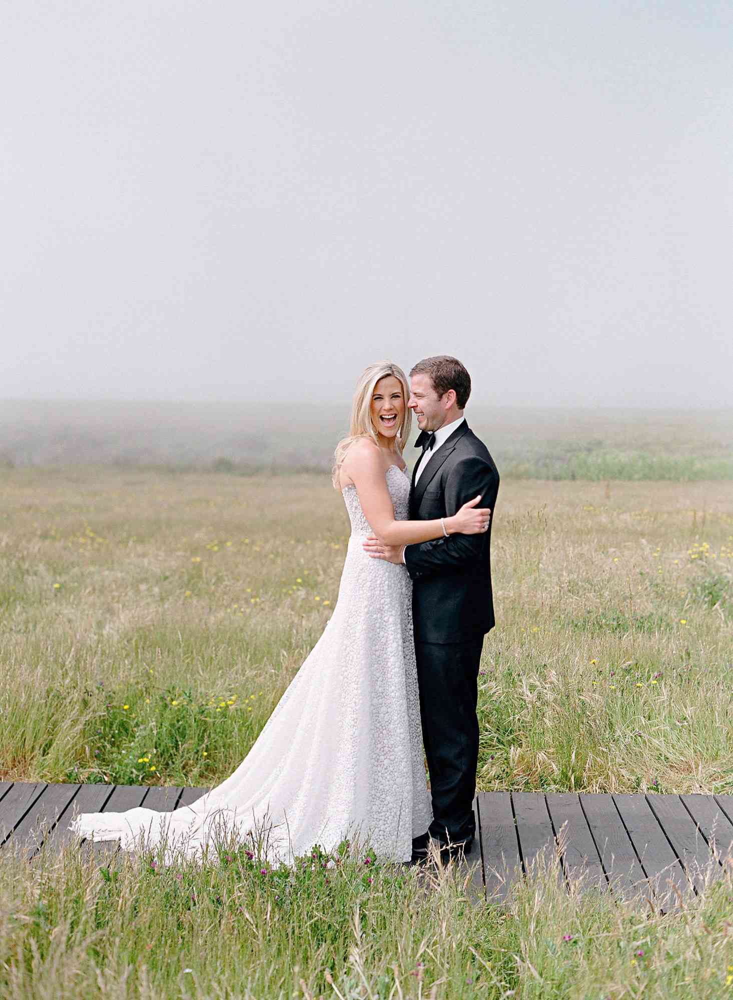 whitney zach wedding couple embracing in field bride laughing