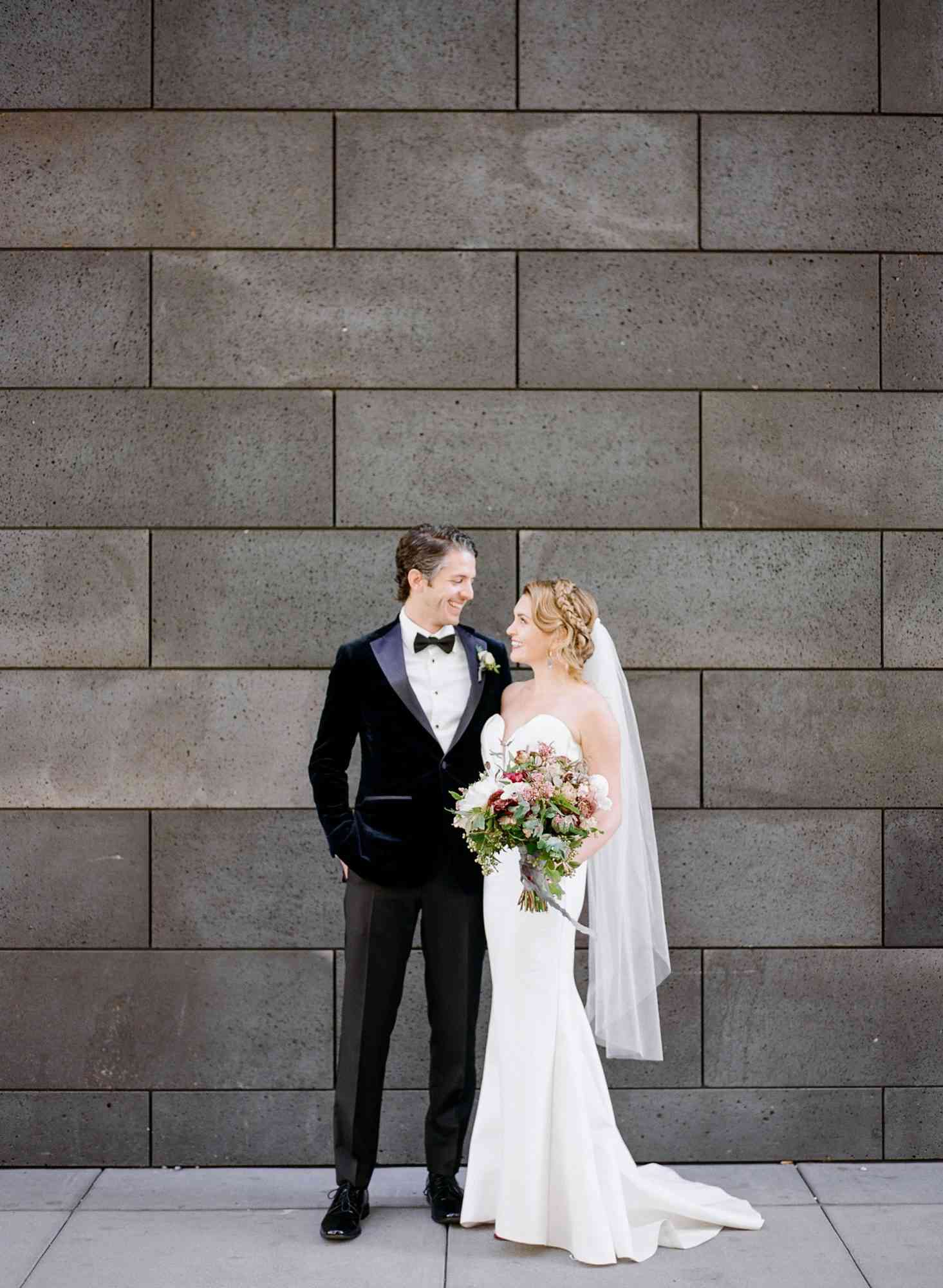 katie andre wedding couple gazing at each other gray brick wall