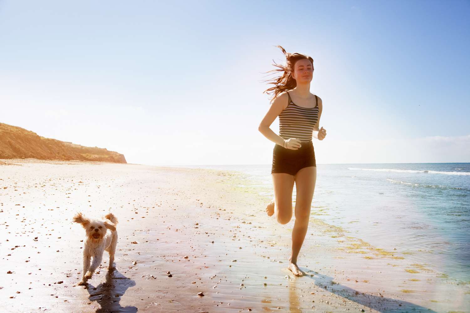 woman and dog running on beach