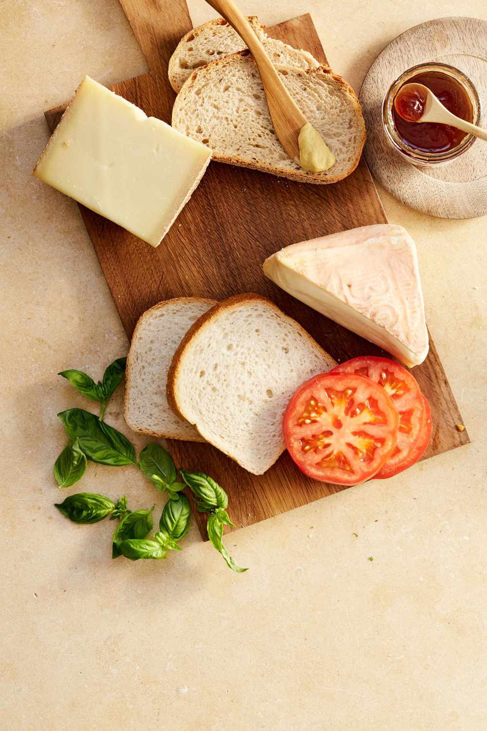 bread butter cheese and tomatoes on cutting board