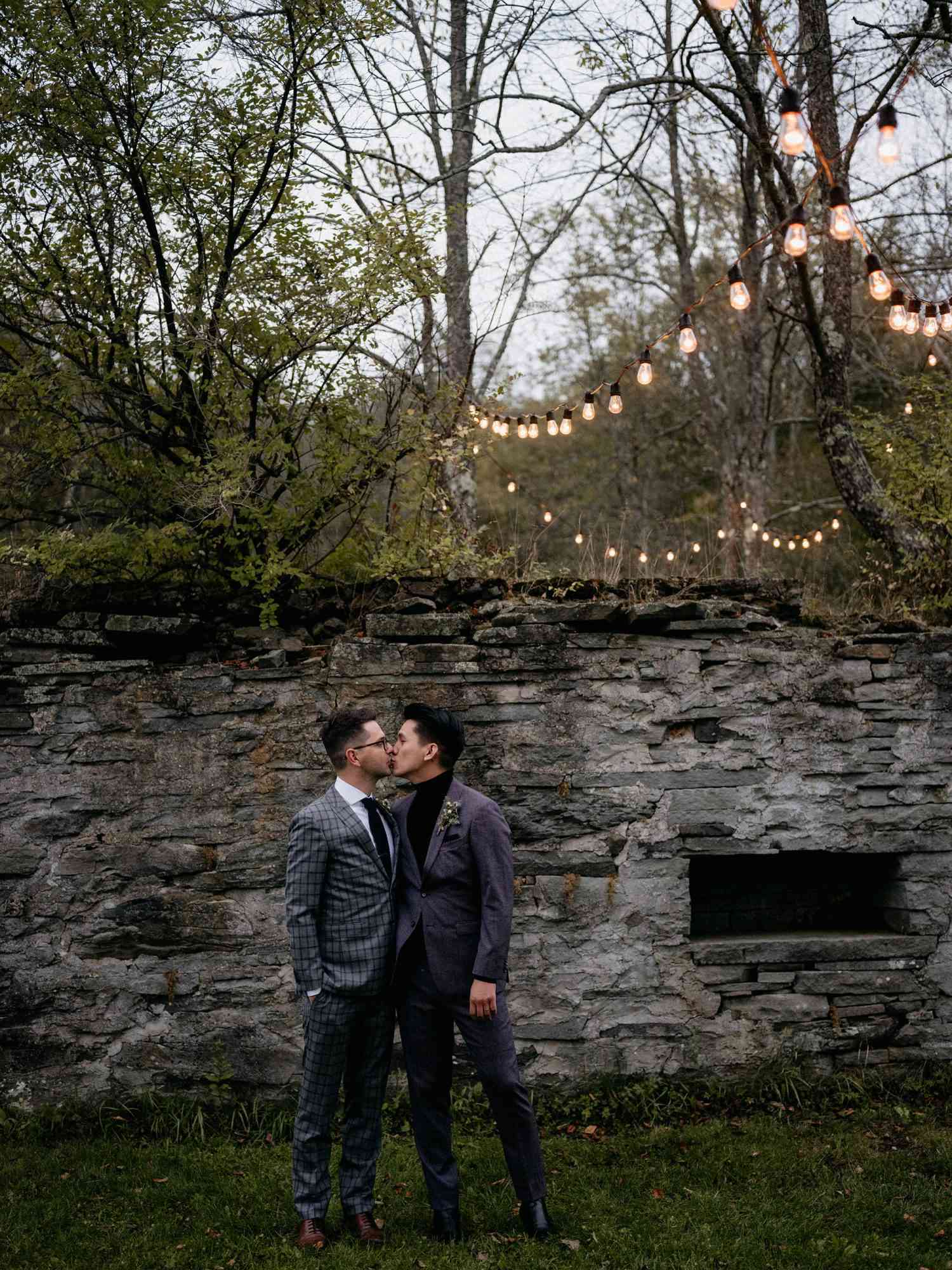 eric eryc wedding grooms in front of stone wall