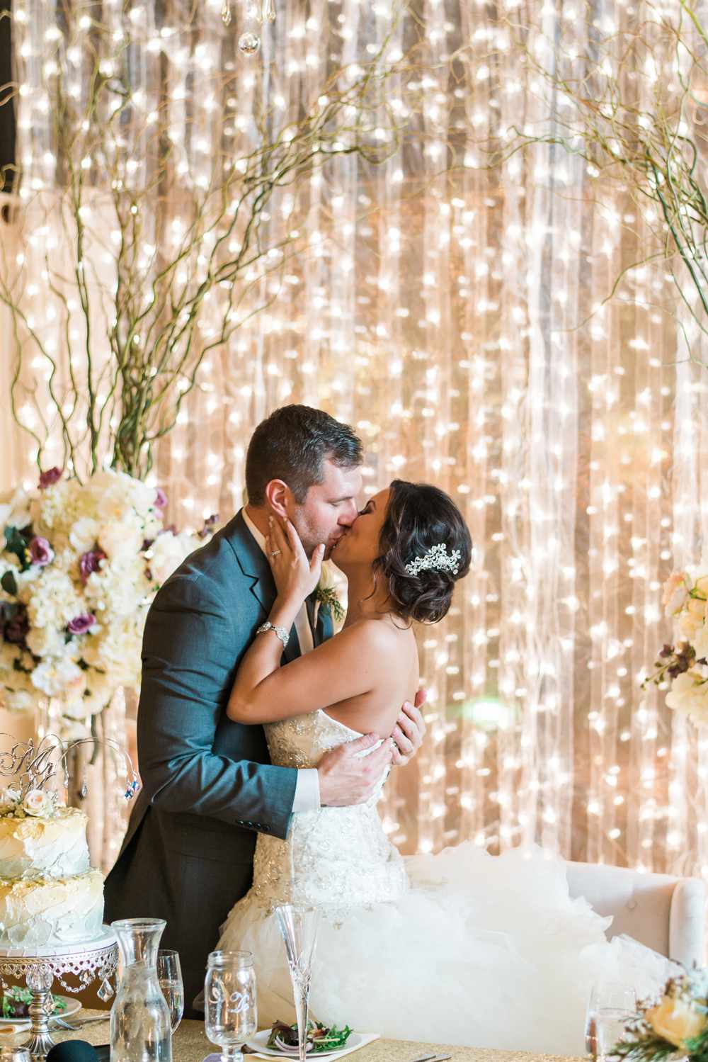 twinkle lights against reception wall with couple kissing